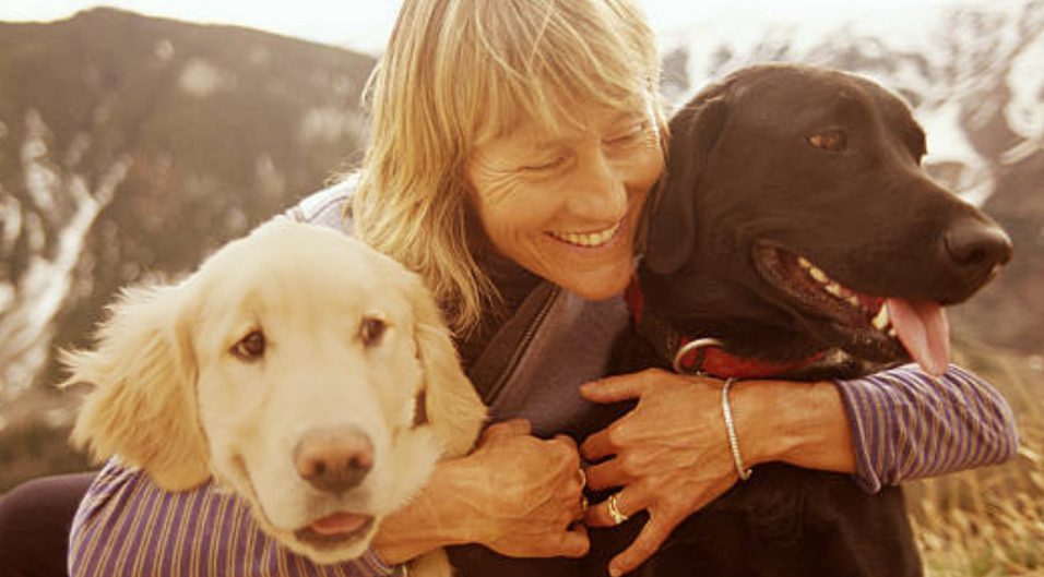 Woman Hugging Two Dogs